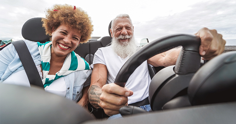 A happy, joyful couple driving their battery electric vehicle on the highway.