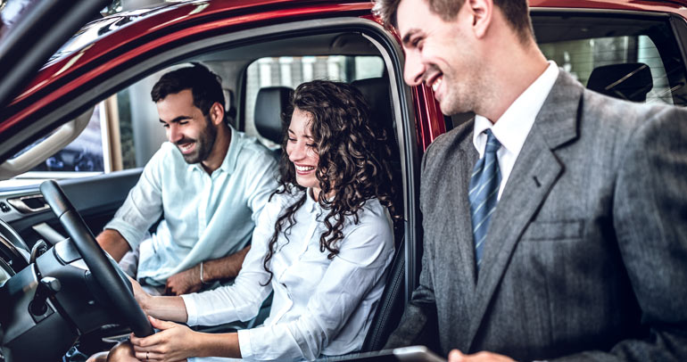 Couple sitting in a car while shopping at a dealership