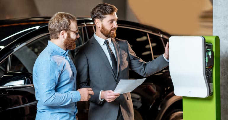 A salesman at a dealership is showing a fleet operator a battery electric vehicle for purchase for his fleet business.