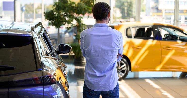 A man looking at different brands of battery electric vehicles.