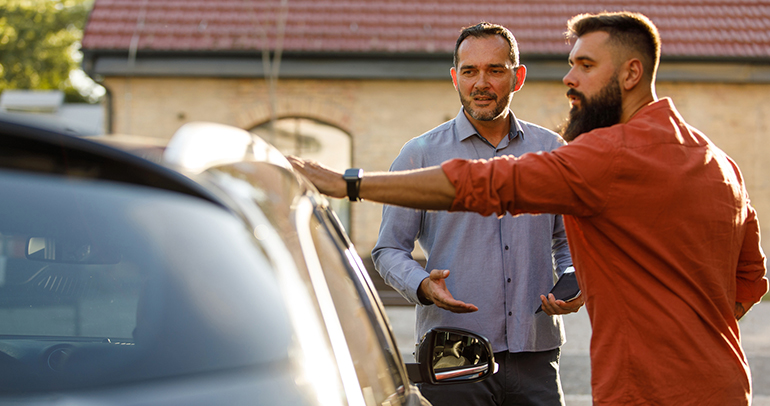 Image of a car salesman talking to a man interested in buying a used battery electric vehicle